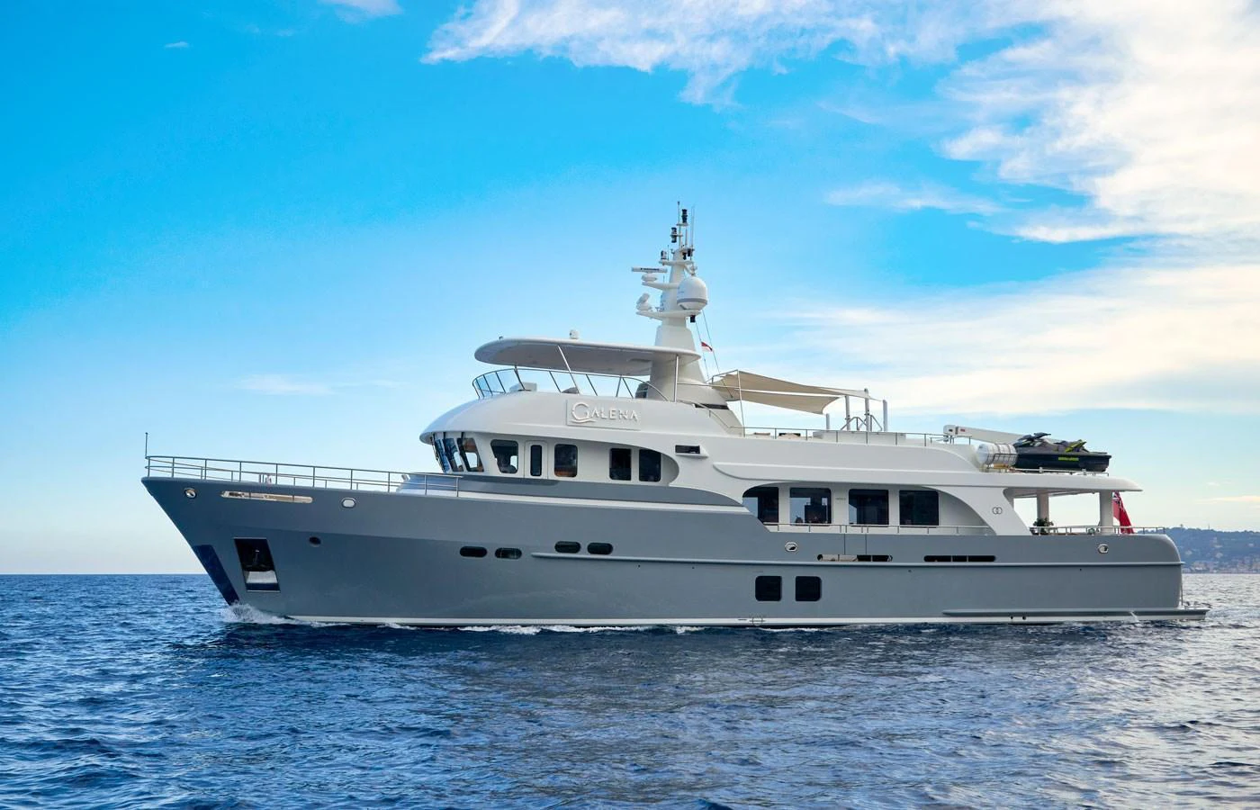A luxurious yacht cruising on calm waters under a clear blue sky. aboard GALENA Yacht for Sale