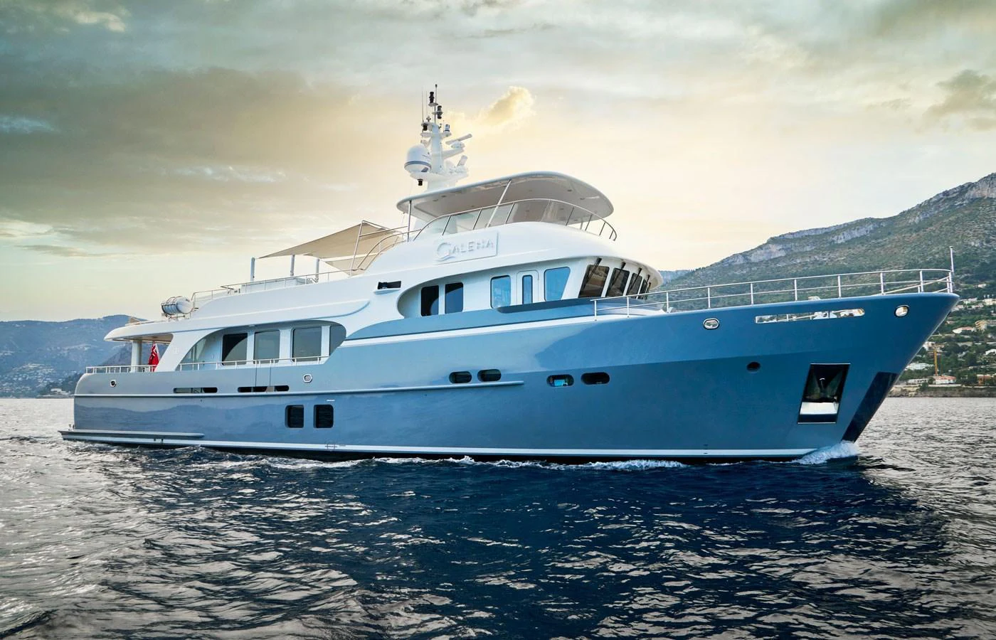 A luxurious yacht glides gracefully on the water with a stunning backdrop of mountains and a serene sky. aboard GALENA Yacht for Sale