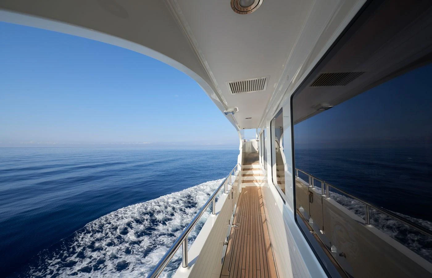 The side deck offers a stunning view of the open sea, with sleek railings and a polished wooden walkway. aboard GALENA Yacht for Sale