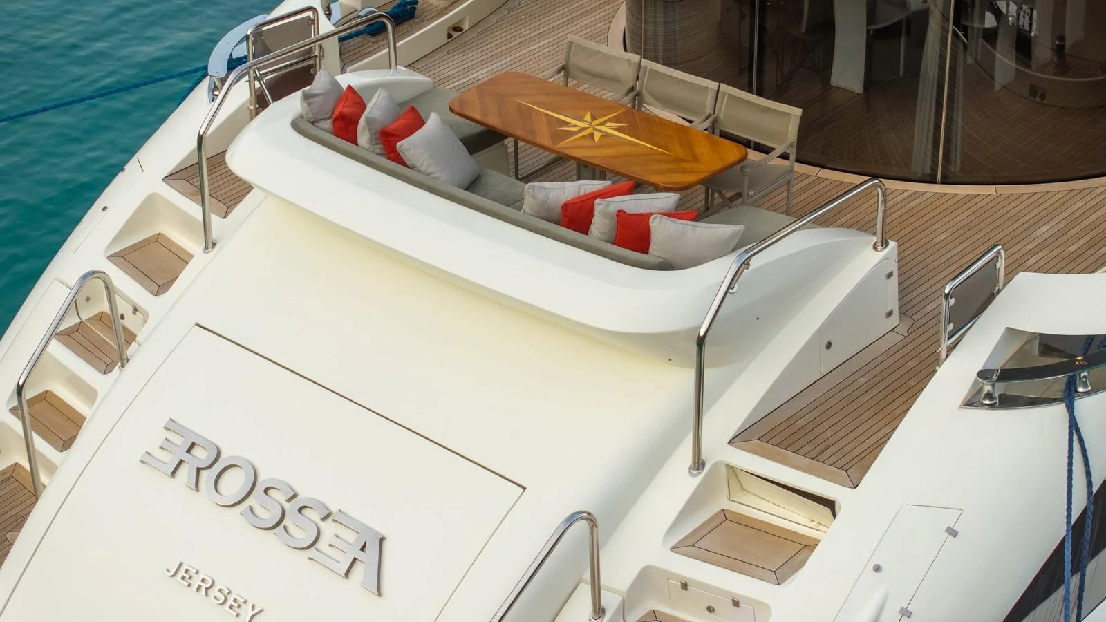 The aft deck features a stylish seating area with plush cushions and a wooden table, perfect for alfresco dining. aboard EROSSEA Yacht for Sale