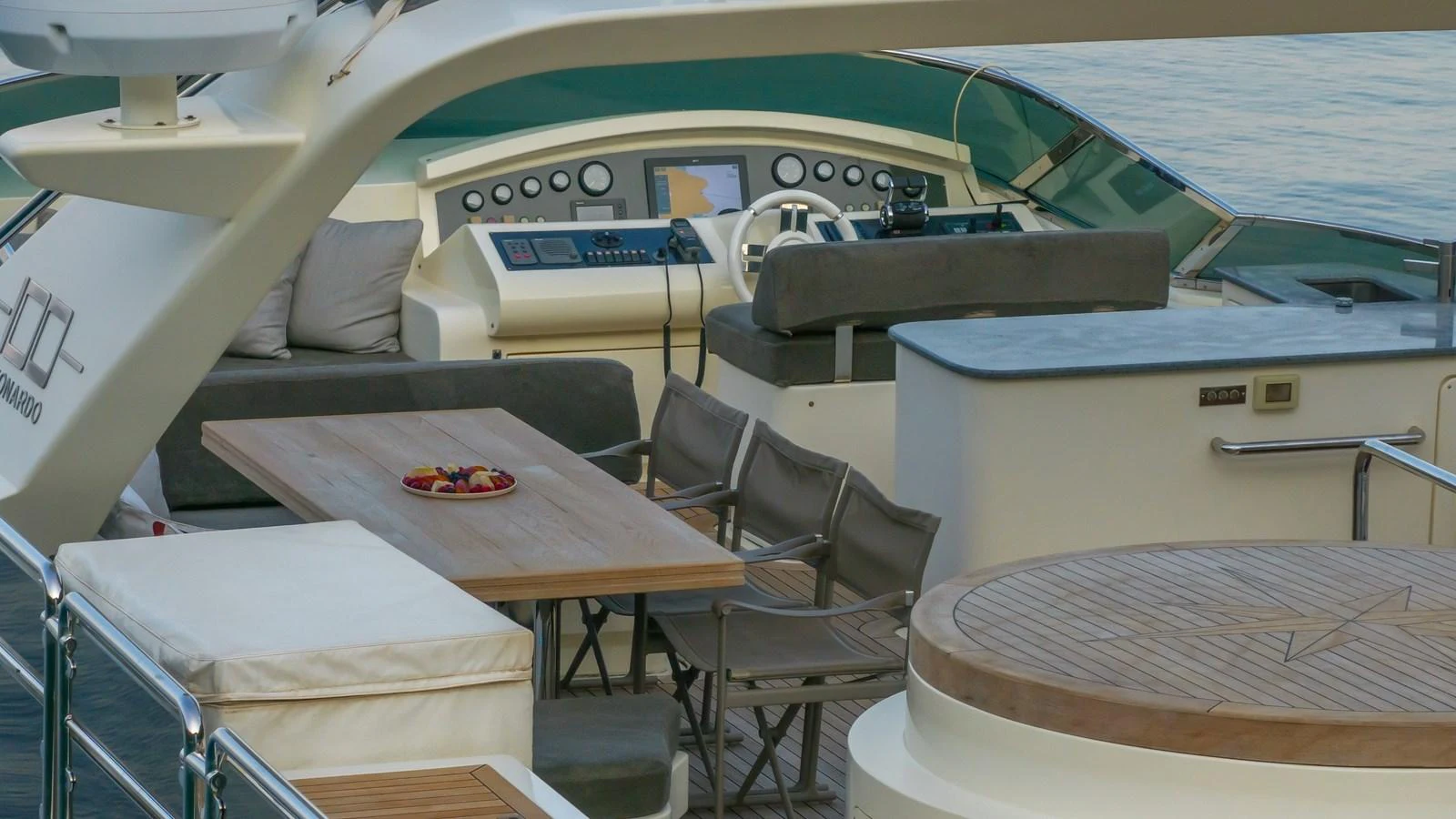 The flybridge features a helm station, a dining area with a wooden table, and comfortable seating. aboard EROSSEA Yacht for Sale