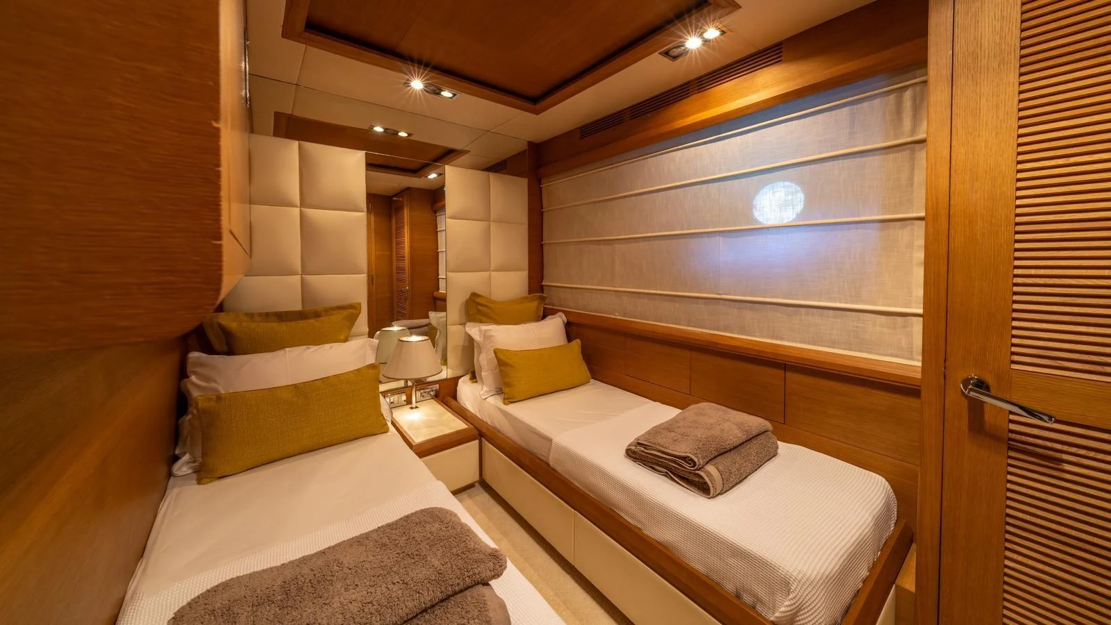 The twin stateroom features two single beds with luxurious linens and warm wood finishes. aboard EROSSEA Yacht for Sale