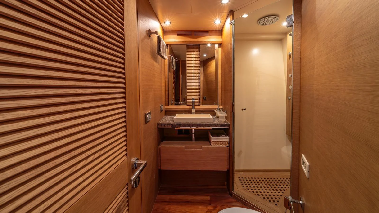 The yacht's bathroom features elegant wood paneling and modern fixtures. aboard EROSSEA Yacht for Sale