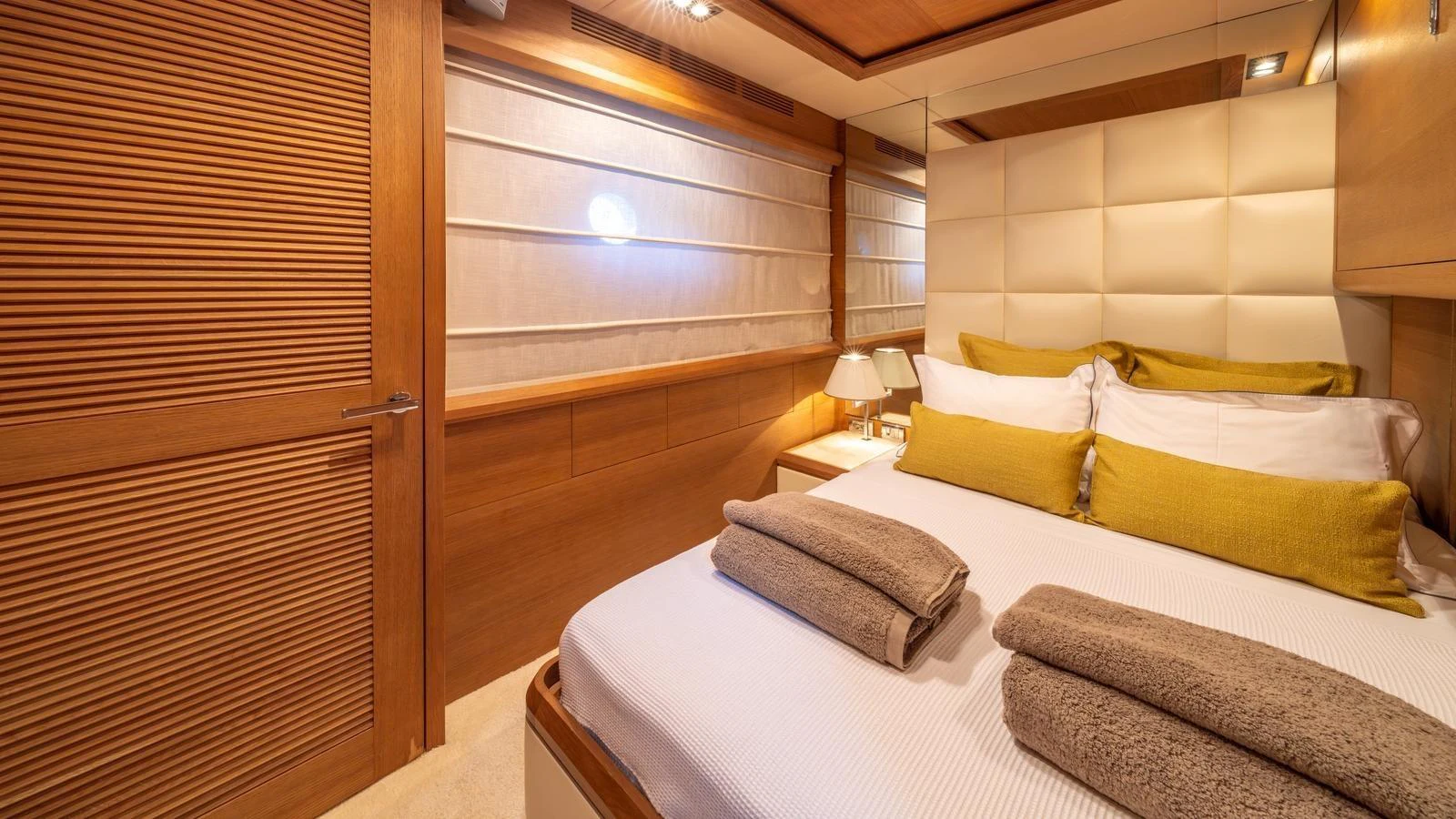 The stateroom features a cozy bed with plush linens and warm wooden accents. aboard EROSSEA Yacht for Sale
