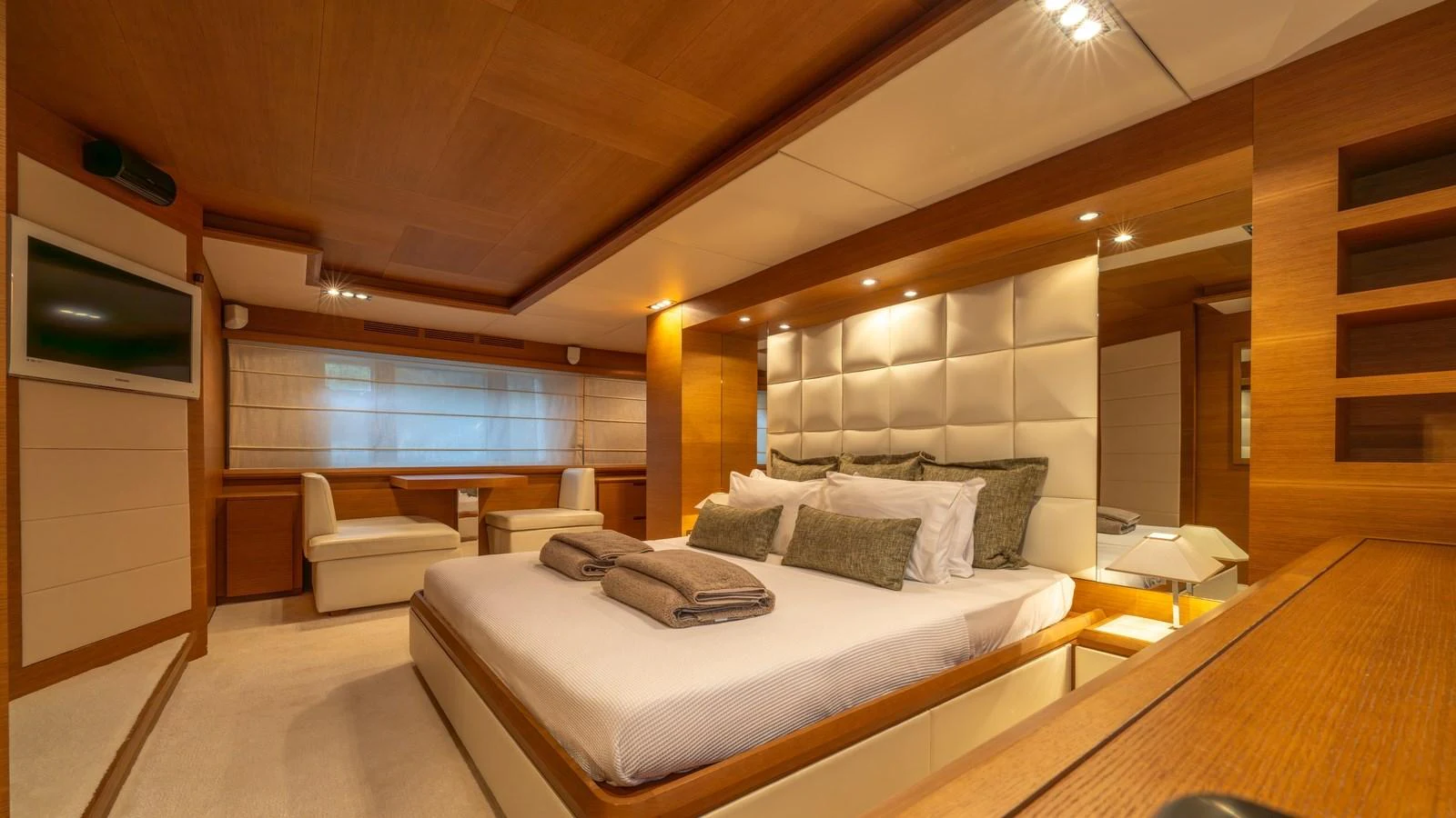 The master stateroom features a luxurious bed with plush pillows and warm wood accents. aboard EROSSEA Yacht for Sale