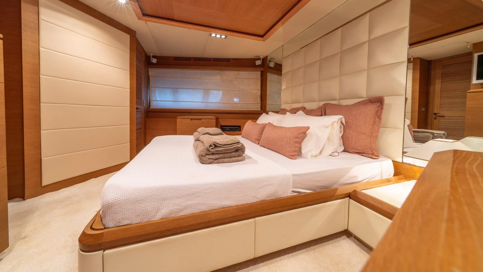 The master stateroom features a luxurious bed with plush pillows and elegant wood finishes. aboard EROSSEA Yacht for Sale