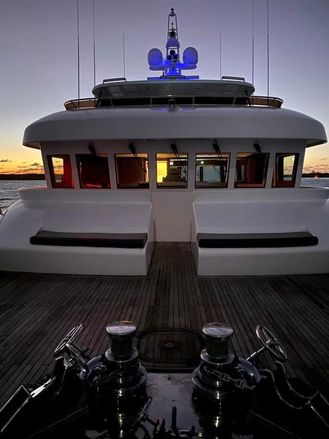 The aft deck of the yacht is beautifully illuminated at dusk, showcasing its sleek design and inviting seating area. aboard SAMSARA Yacht for Sale