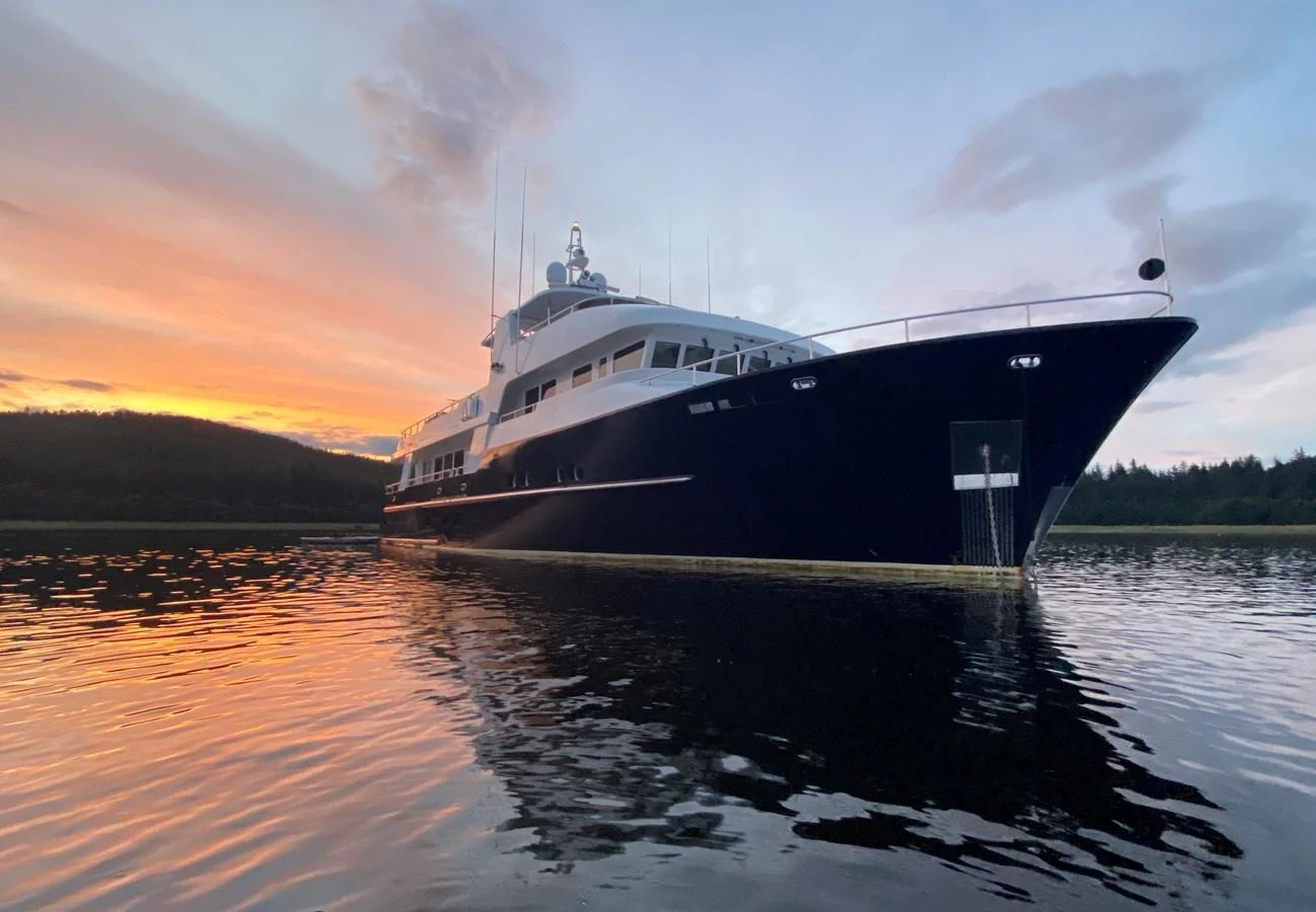 A stunning yacht is anchored on calm waters at sunset, showcasing its sleek design and elegant presence. aboard SAMSARA Yacht for Sale