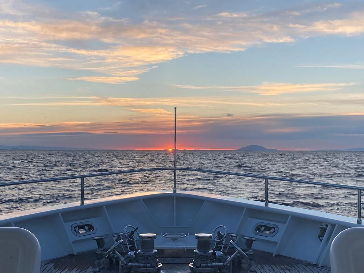 The bow of the yacht overlooks a serene ocean sunset. aboard SAMSARA Yacht for Sale