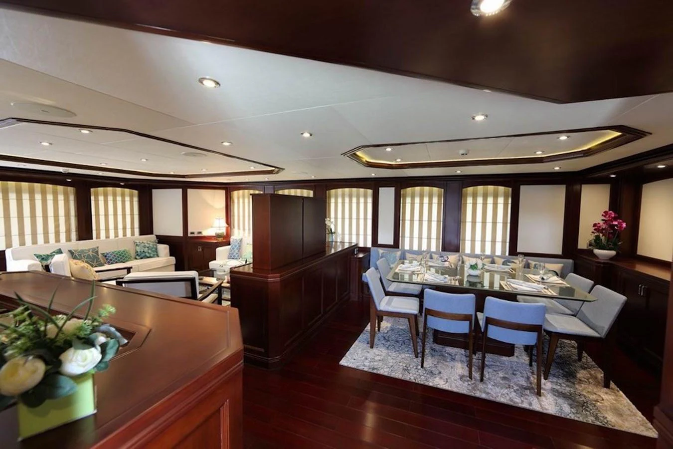 A luxurious dining area with a beautifully set table and comfortable seating, adjacent to a cozy lounge space. aboard SAMSARA Yacht for Sale