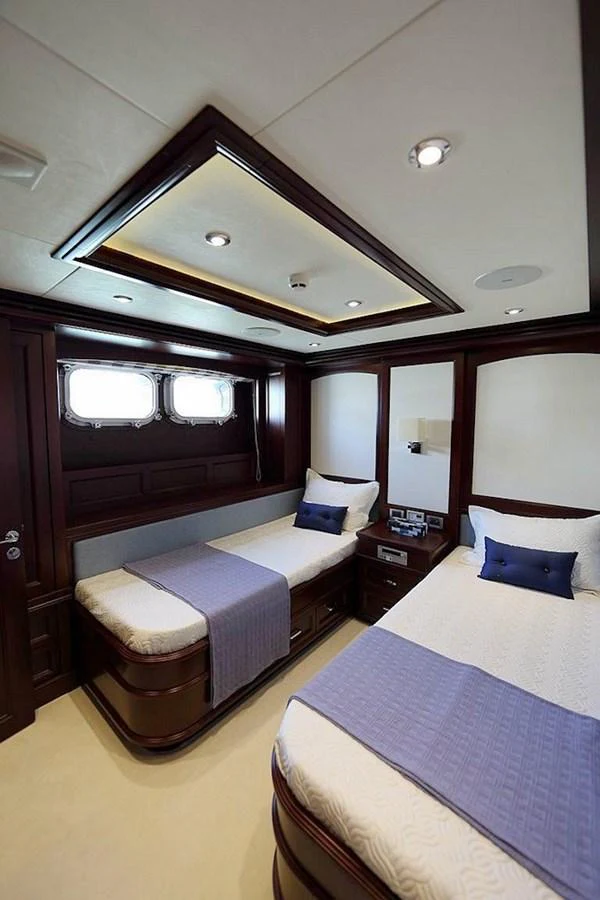 The guest stateroom features twin beds with elegant wood paneling and soft lighting. aboard SAMSARA Yacht for Sale