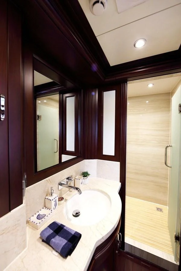 The yacht's bathroom features elegant wood finishes and a spacious shower area. aboard SAMSARA Yacht for Sale