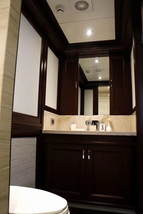 A luxurious bathroom with dark wood cabinetry and elegant fixtures. aboard SAMSARA Yacht for Sale
