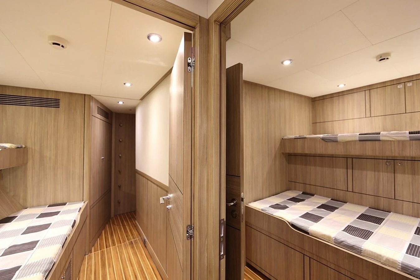 The image showcases a cozy cabin with twin bunk beds and warm wooden finishes. aboard SAMSARA Yacht for Sale