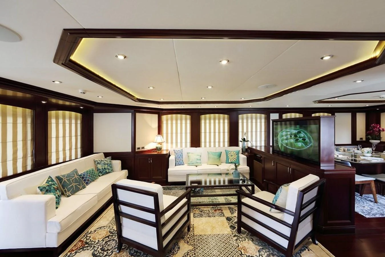 The salon features elegant seating with plush white sofas and stylish armchairs, complemented by rich wood accents and a sophisticated decor. aboard SAMSARA Yacht for Sale