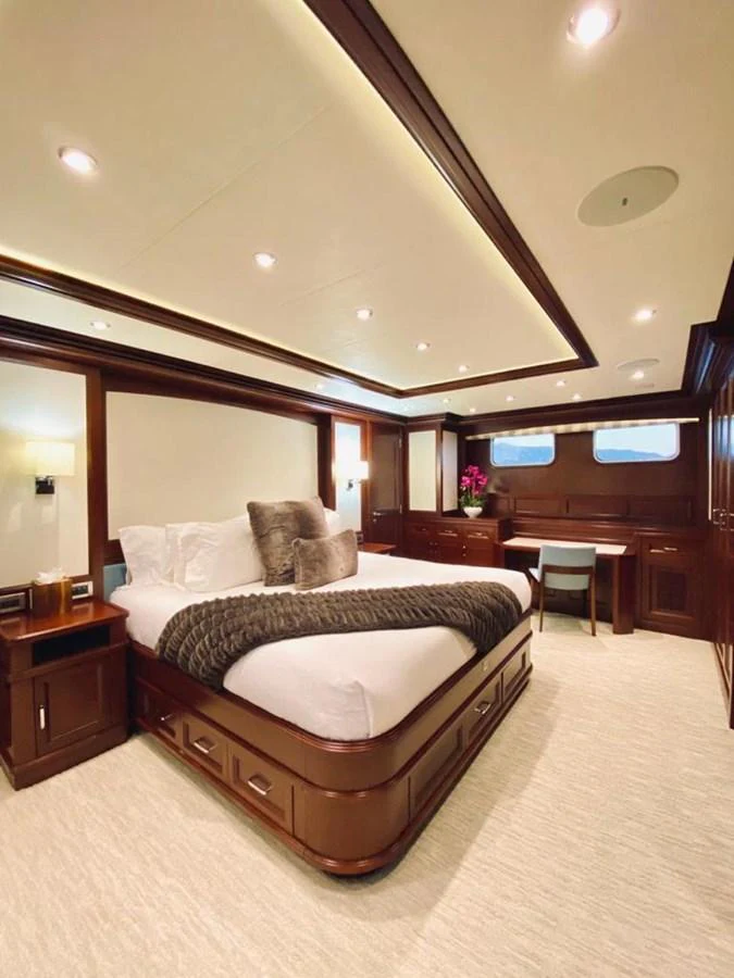 The stateroom features elegant wood finishes and luxurious bedding, creating a warm and inviting atmosphere. aboard SAMSARA Yacht for Sale