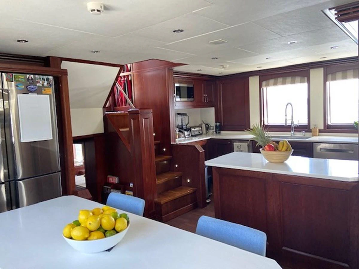 The yacht's galley features modern appliances, rich wood cabinetry, and a spacious dining area. aboard SAMSARA Yacht for Sale