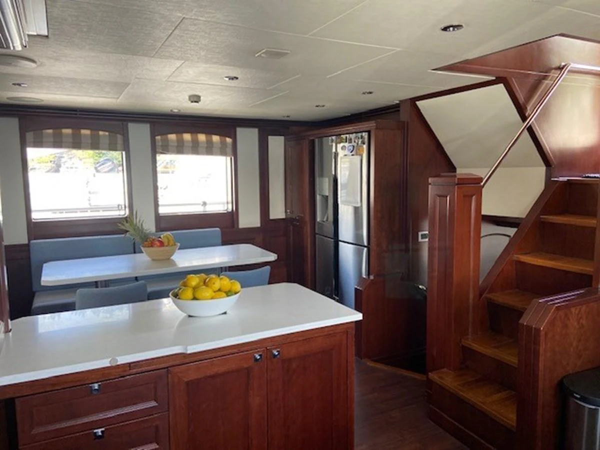 The yacht's galley features a modern kitchen area with a dining space and wooden staircase. aboard SAMSARA Yacht for Sale