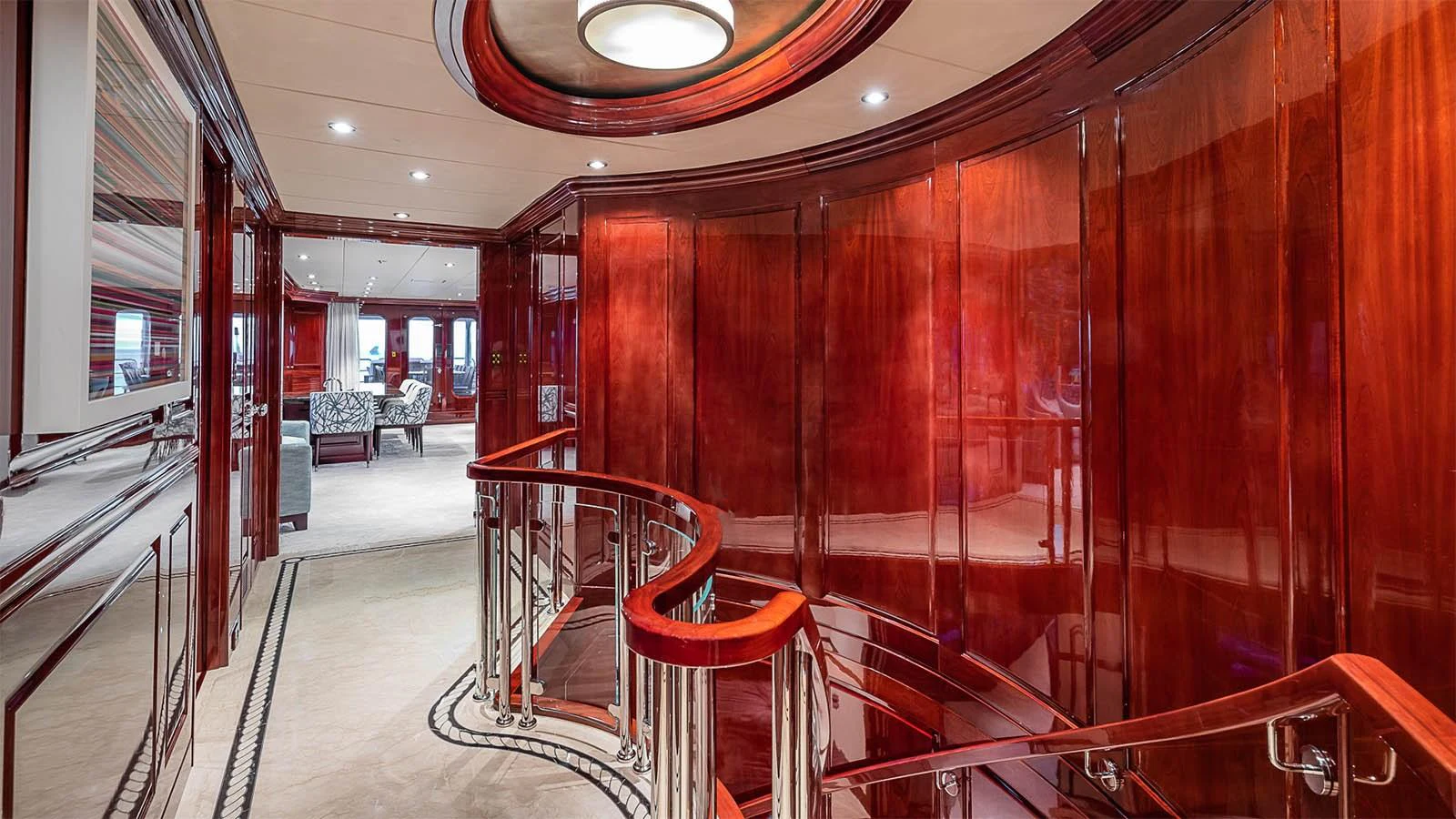 The yacht's interior features a luxurious wooden staircase with polished railings leading to a spacious and elegant lounge area. aboard CARTE BLANCHE Yacht for Sale