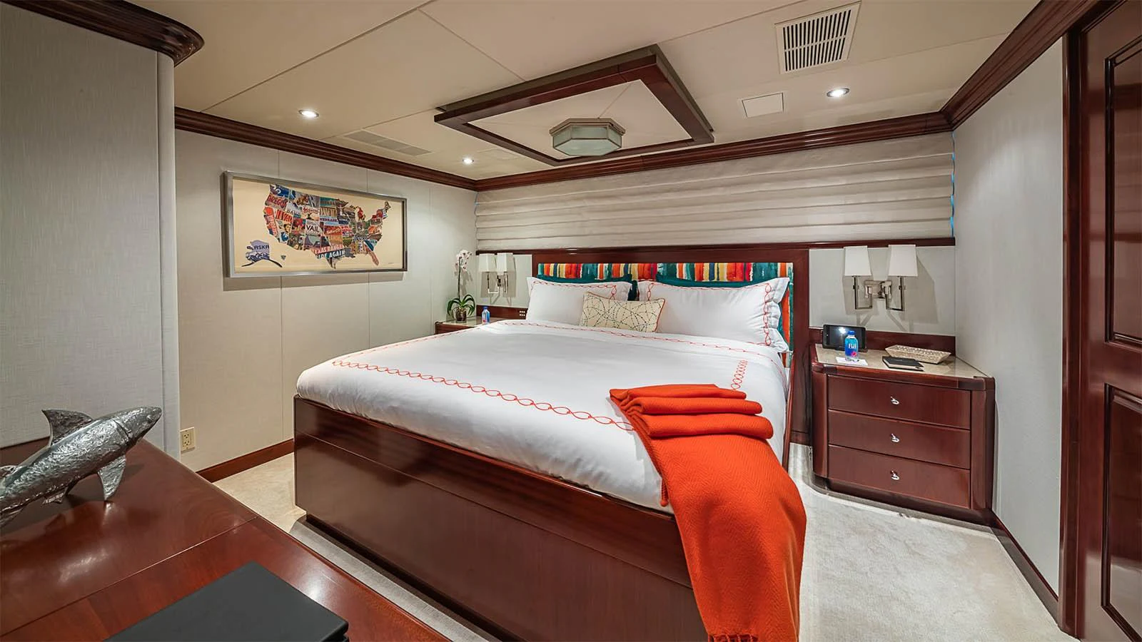 The stateroom features a spacious bed with vibrant accents and elegant wood furnishings. aboard CARTE BLANCHE Yacht for Sale