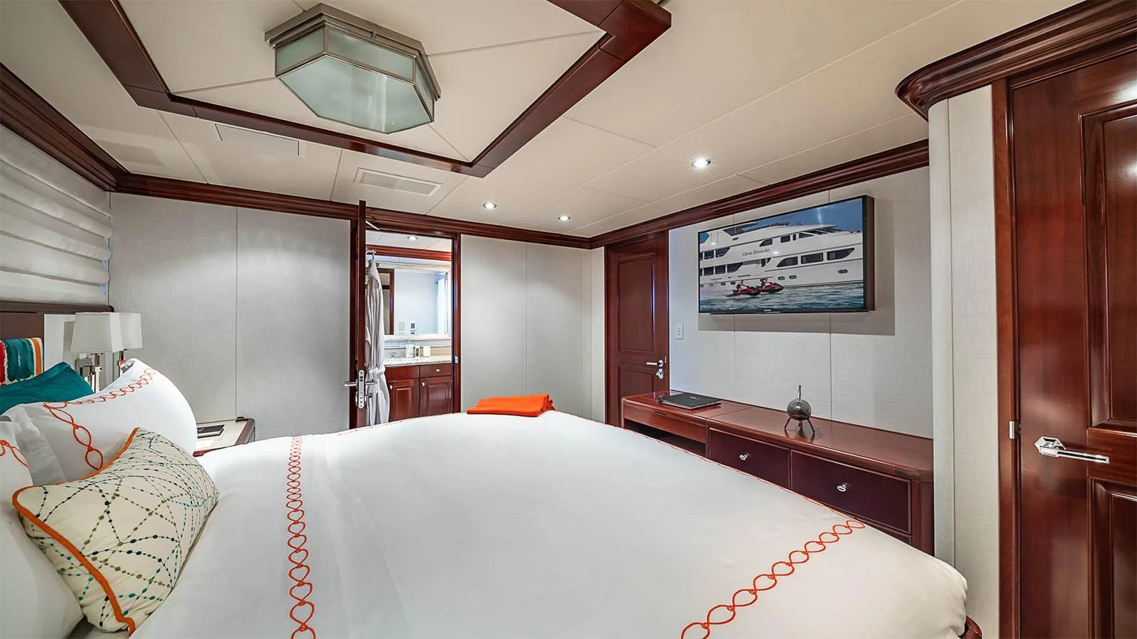 A luxurious stateroom featuring a large bed, elegant wood finishes, and modern amenities. aboard CARTE BLANCHE Yacht for Sale