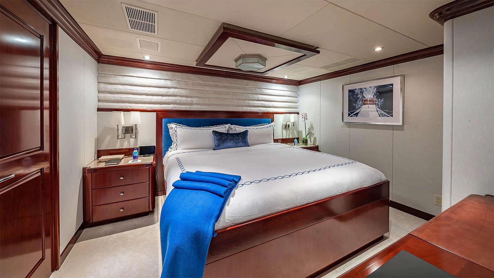 The master stateroom features a luxurious bed with elegant bedding and warm wood accents. aboard CARTE BLANCHE Yacht for Sale