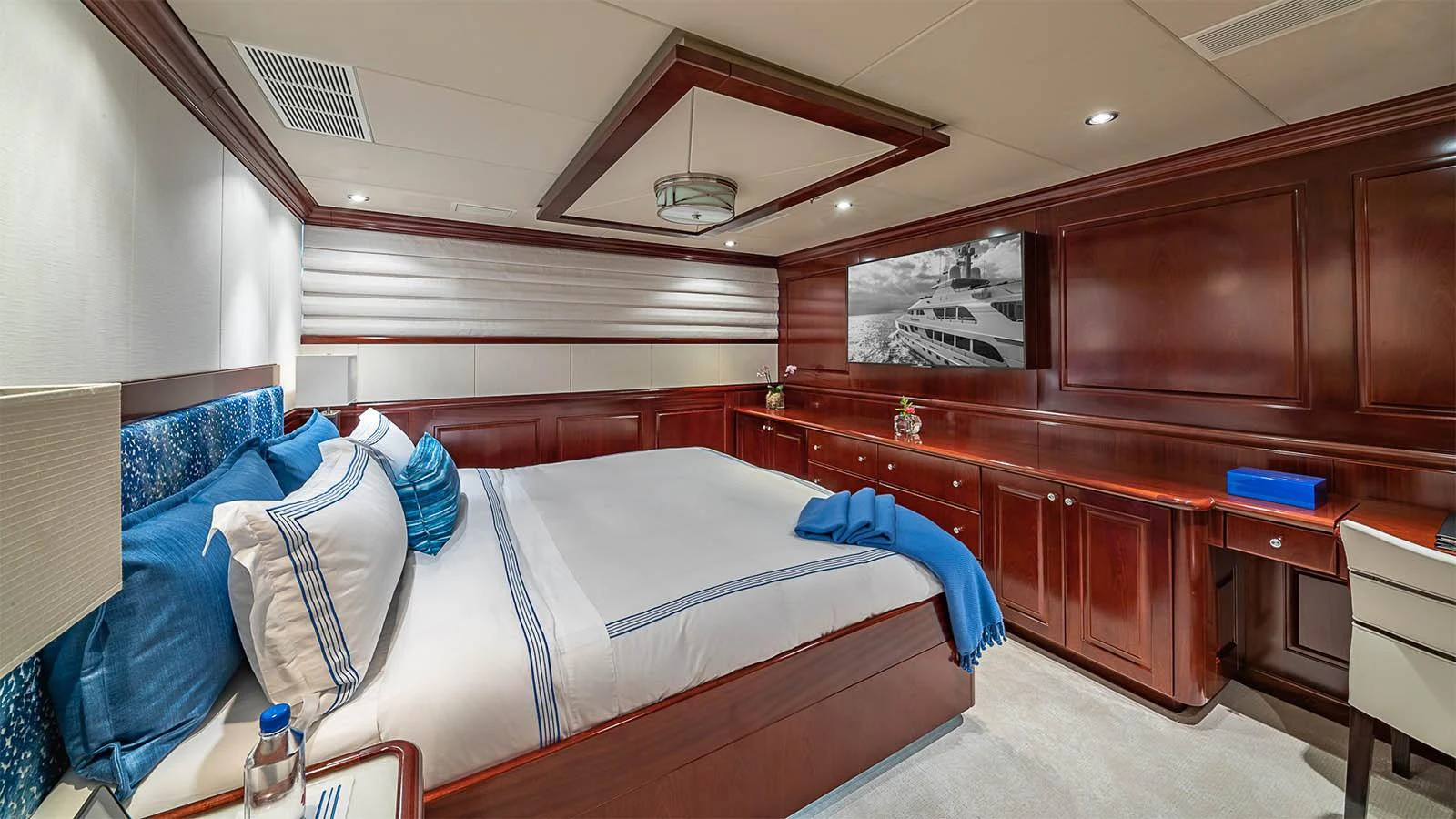The stateroom features a luxurious bed with elegant wood paneling and modern lighting. aboard CARTE BLANCHE Yacht for Sale
