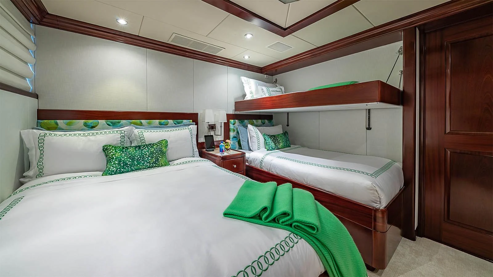 The guest stateroom features comfortable bedding with elegant green accents and a cozy atmosphere. aboard CARTE BLANCHE Yacht for Sale