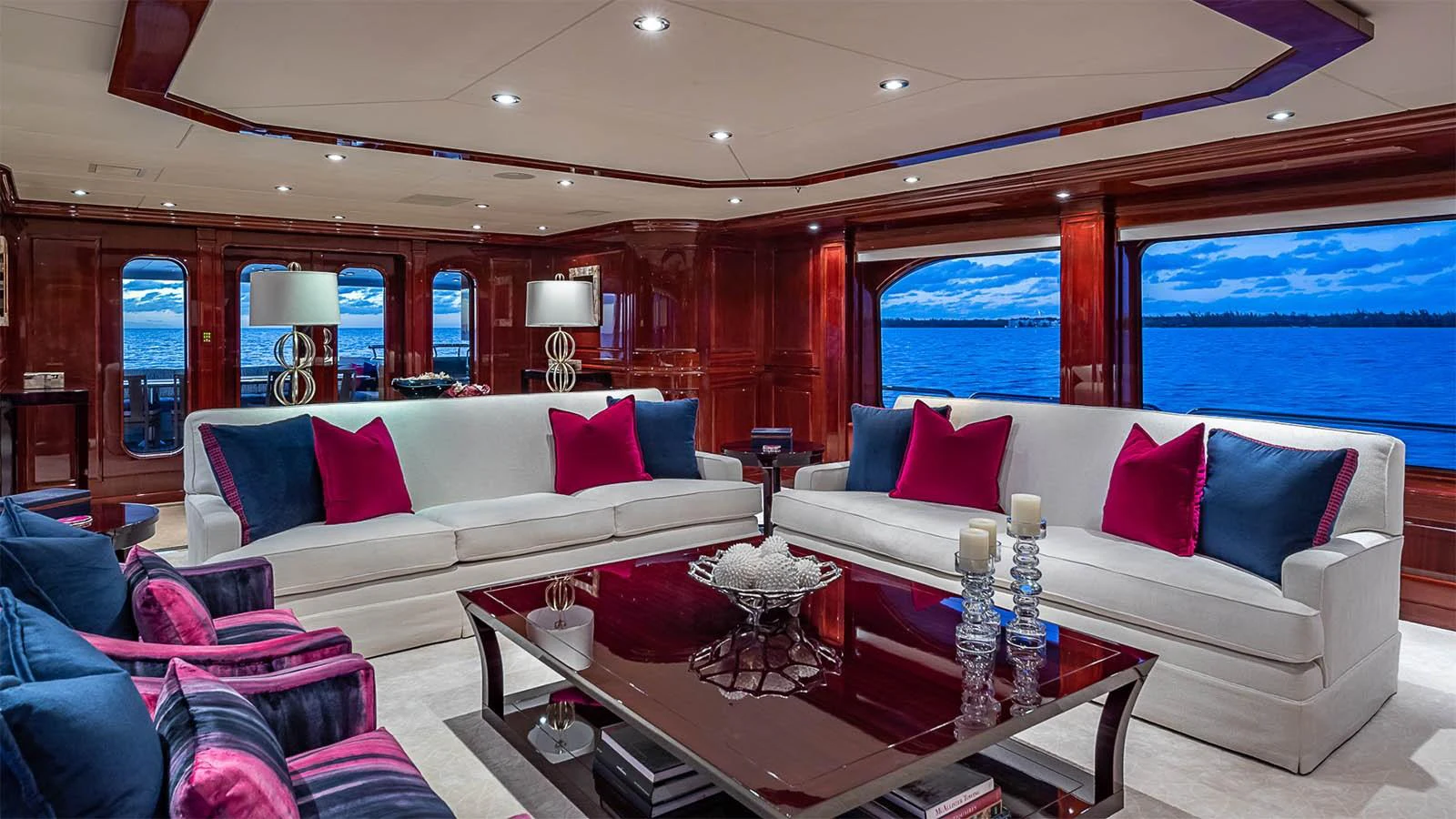 The luxurious salon features plush seating with vibrant accents and expansive windows offering stunning ocean views. aboard CARTE BLANCHE Yacht for Sale