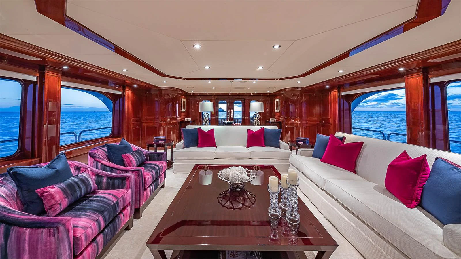 The luxurious salon features elegant seating with vibrant accents and expansive ocean views. aboard CARTE BLANCHE Yacht for Sale