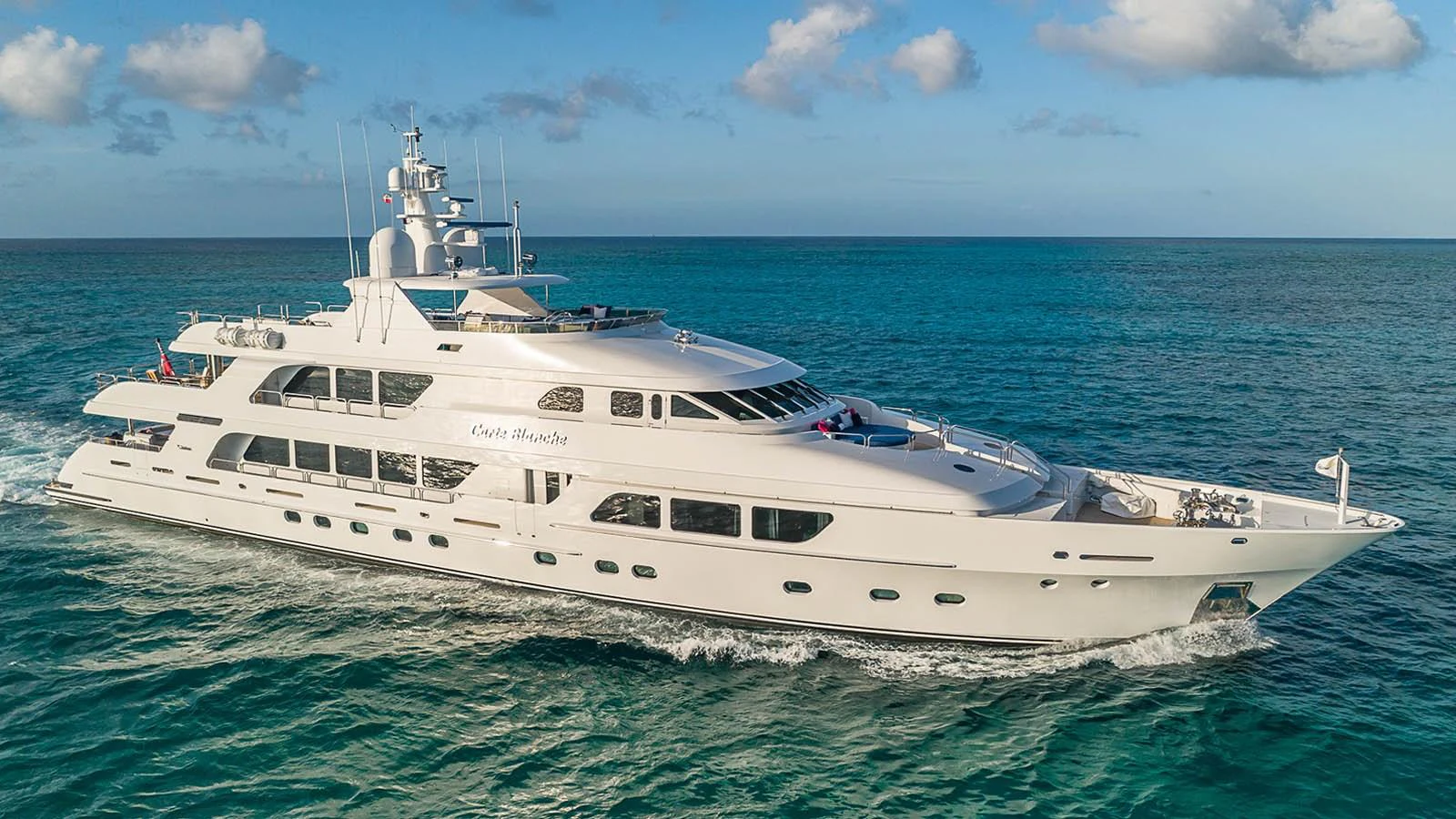 A luxurious yacht glides gracefully across the turquoise waters under a clear blue sky. aboard CARTE BLANCHE Yacht for Sale