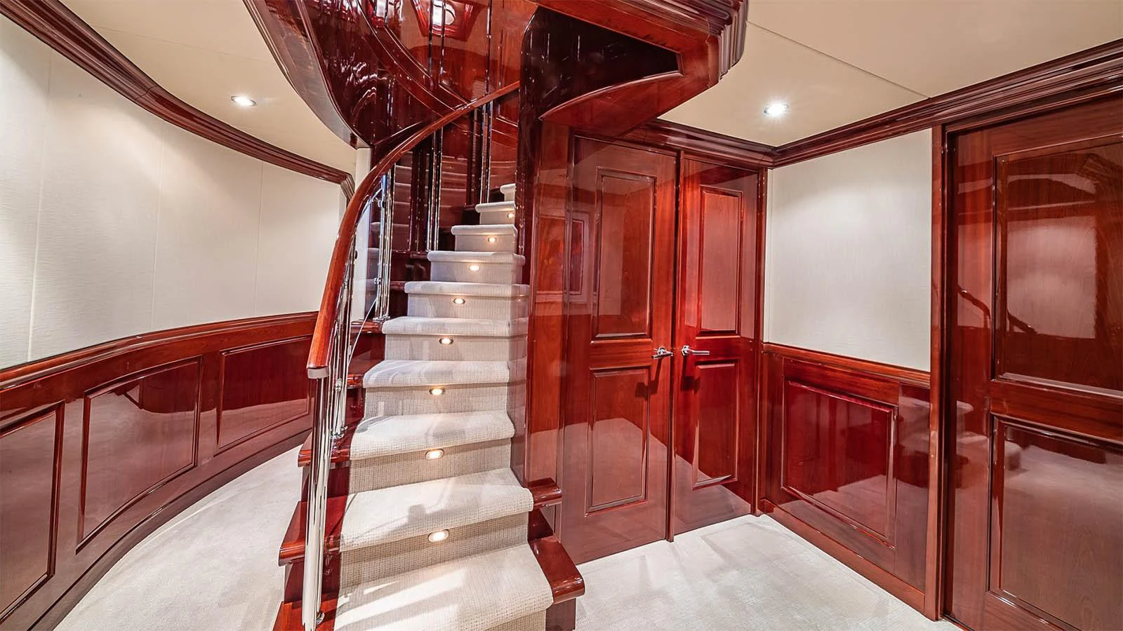 A luxurious interior staircase with polished wood paneling and carpeted steps. aboard CARTE BLANCHE Yacht for Sale