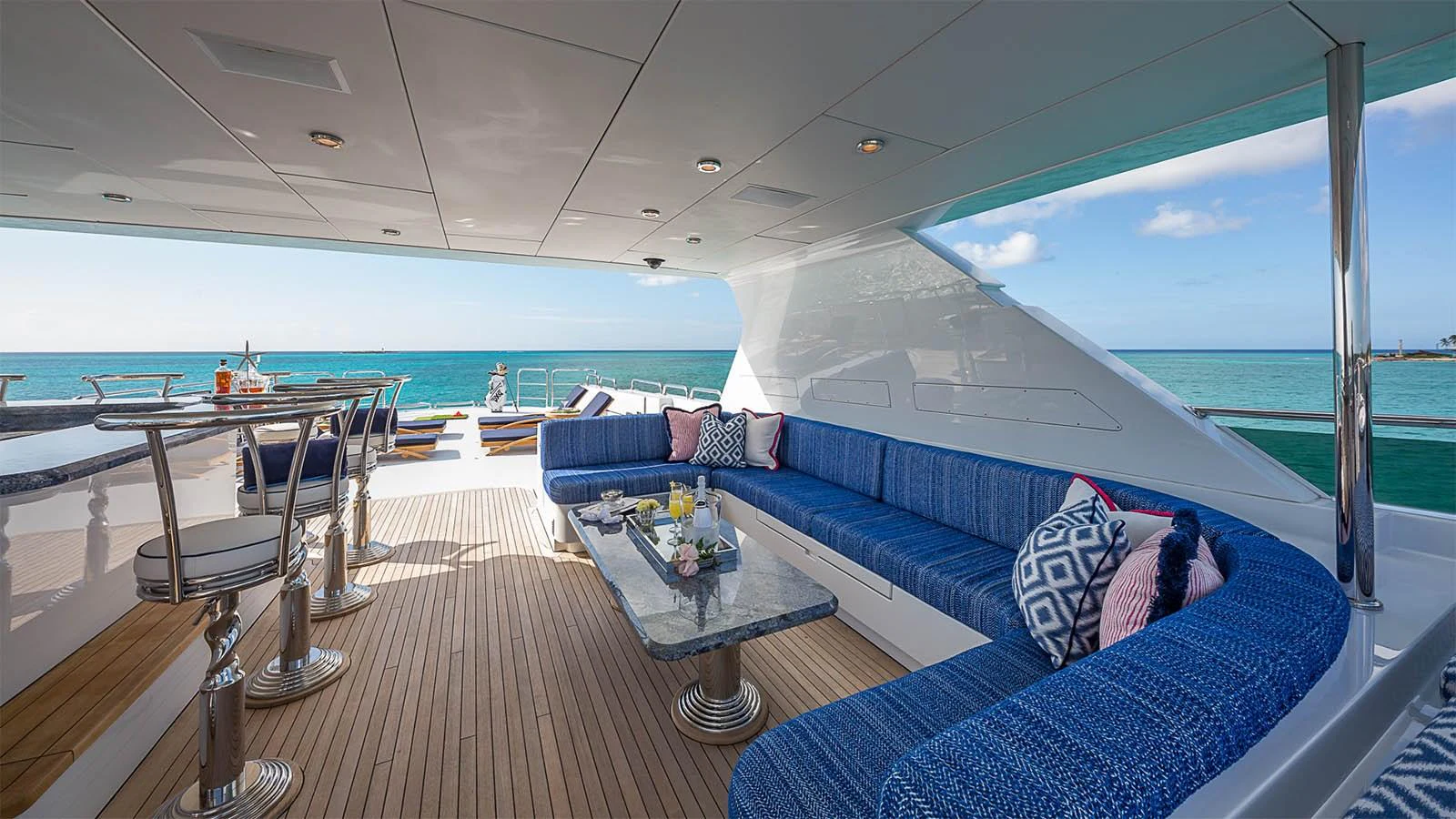 The aft deck features a spacious seating area with plush blue cushions and a stylish bar, perfect for relaxing and entertaining. aboard CARTE BLANCHE Yacht for Sale