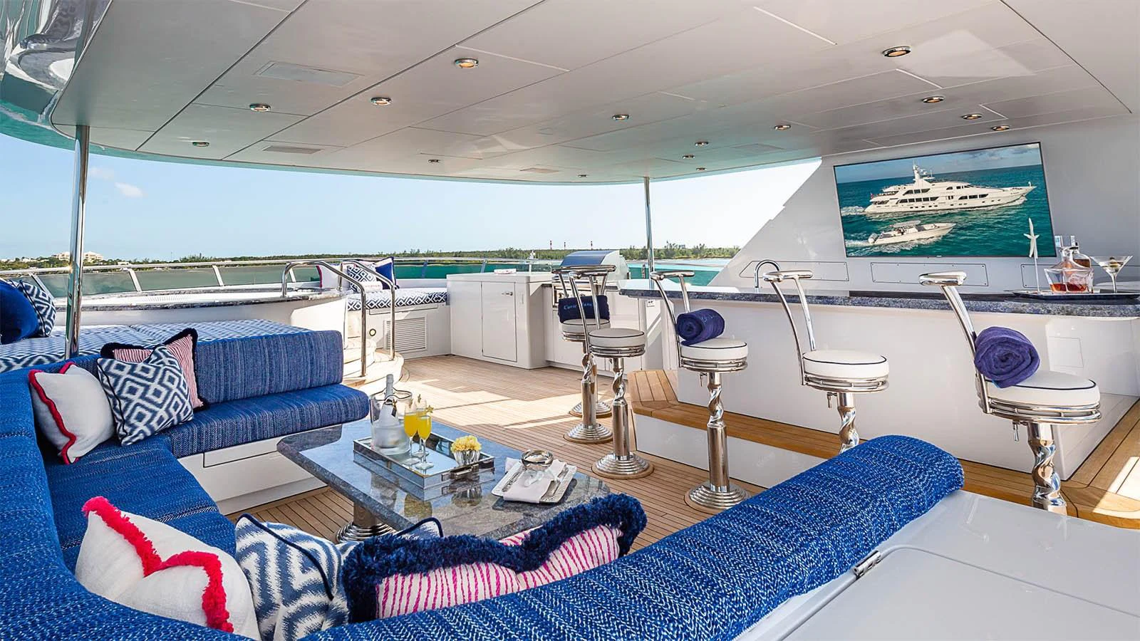 The aft deck features a spacious seating area with plush blue cushions and a bar, perfect for relaxation and entertainment. aboard CARTE BLANCHE Yacht for Sale