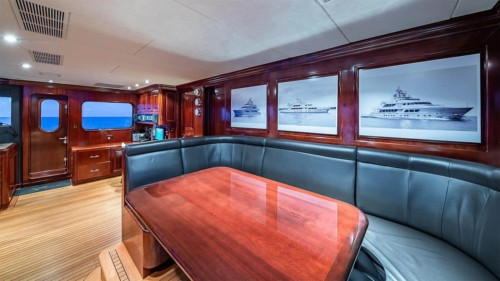 The saloon features a luxurious seating area with rich wood finishes and yacht-themed artwork. aboard CARTE BLANCHE Yacht for Sale
