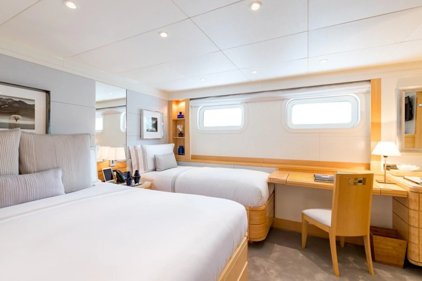 The guest stateroom features twin beds, a writing desk, and ample natural light from the windows. aboard LA TANIA Yacht for Sale