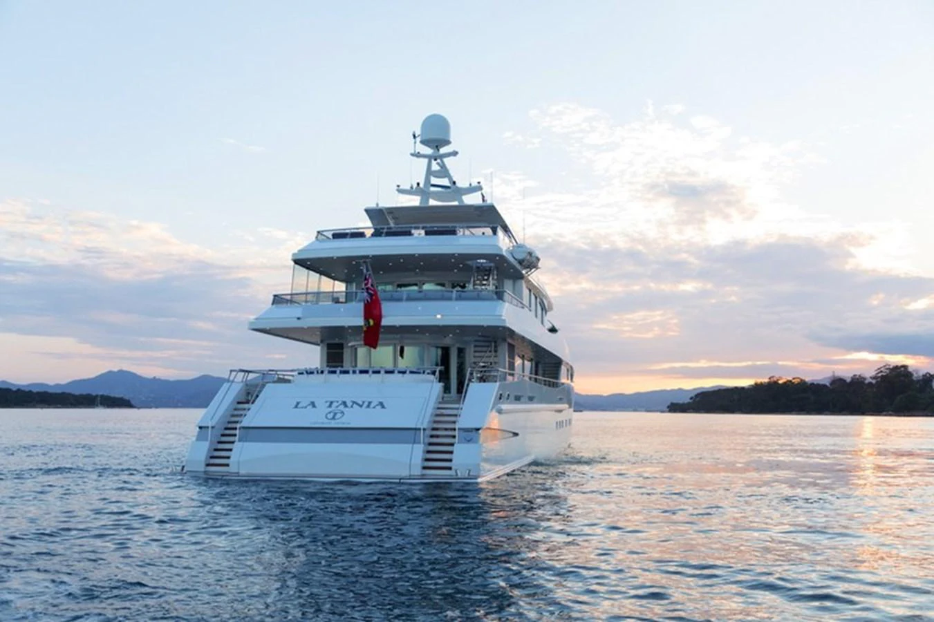 A luxurious yacht is seen cruising on calm waters during a serene sunset. aboard LA TANIA Yacht for Sale