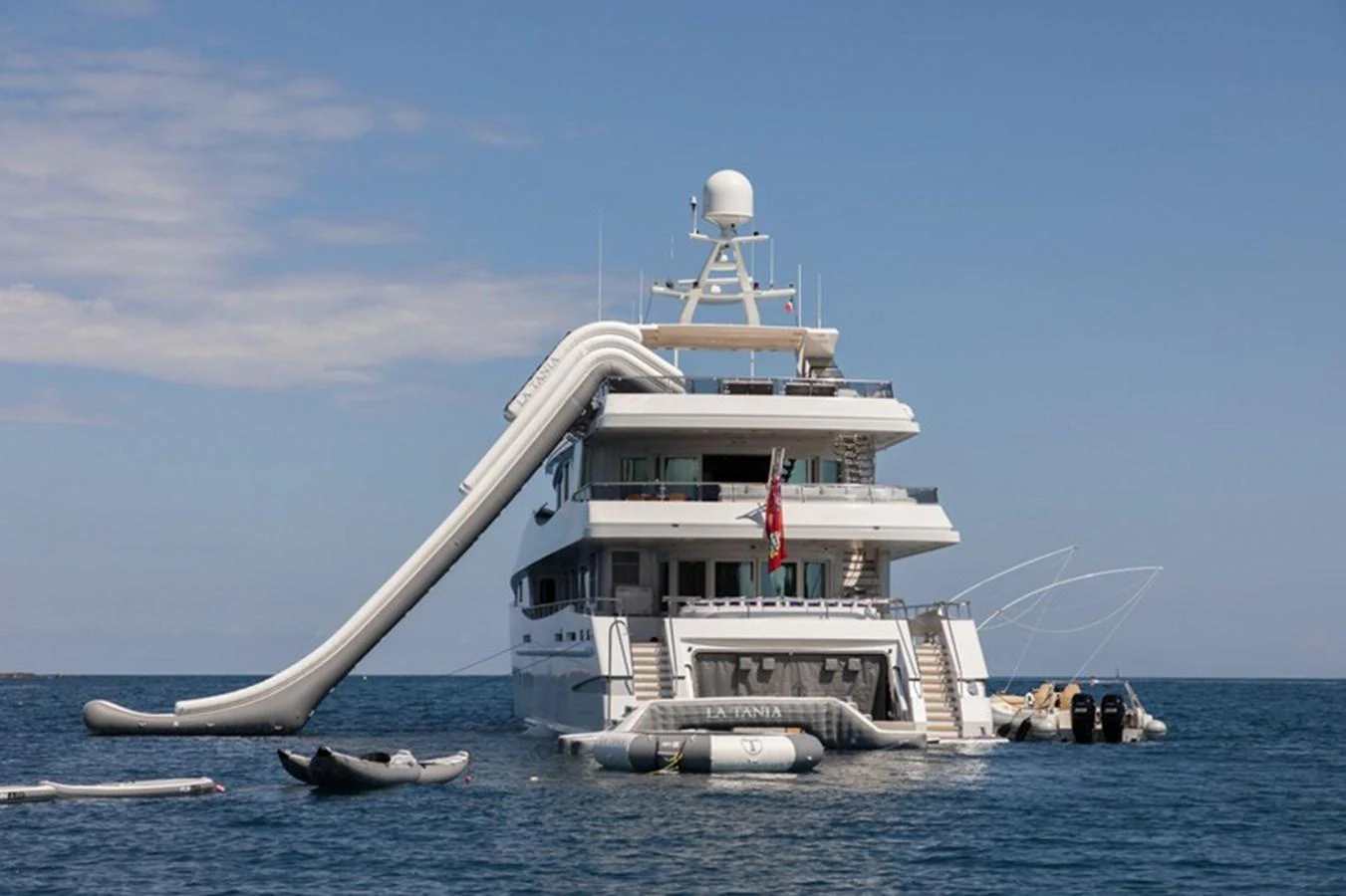 The yacht is anchored in calm waters, featuring an impressive slide and various water toys. aboard LA TANIA Yacht for Sale