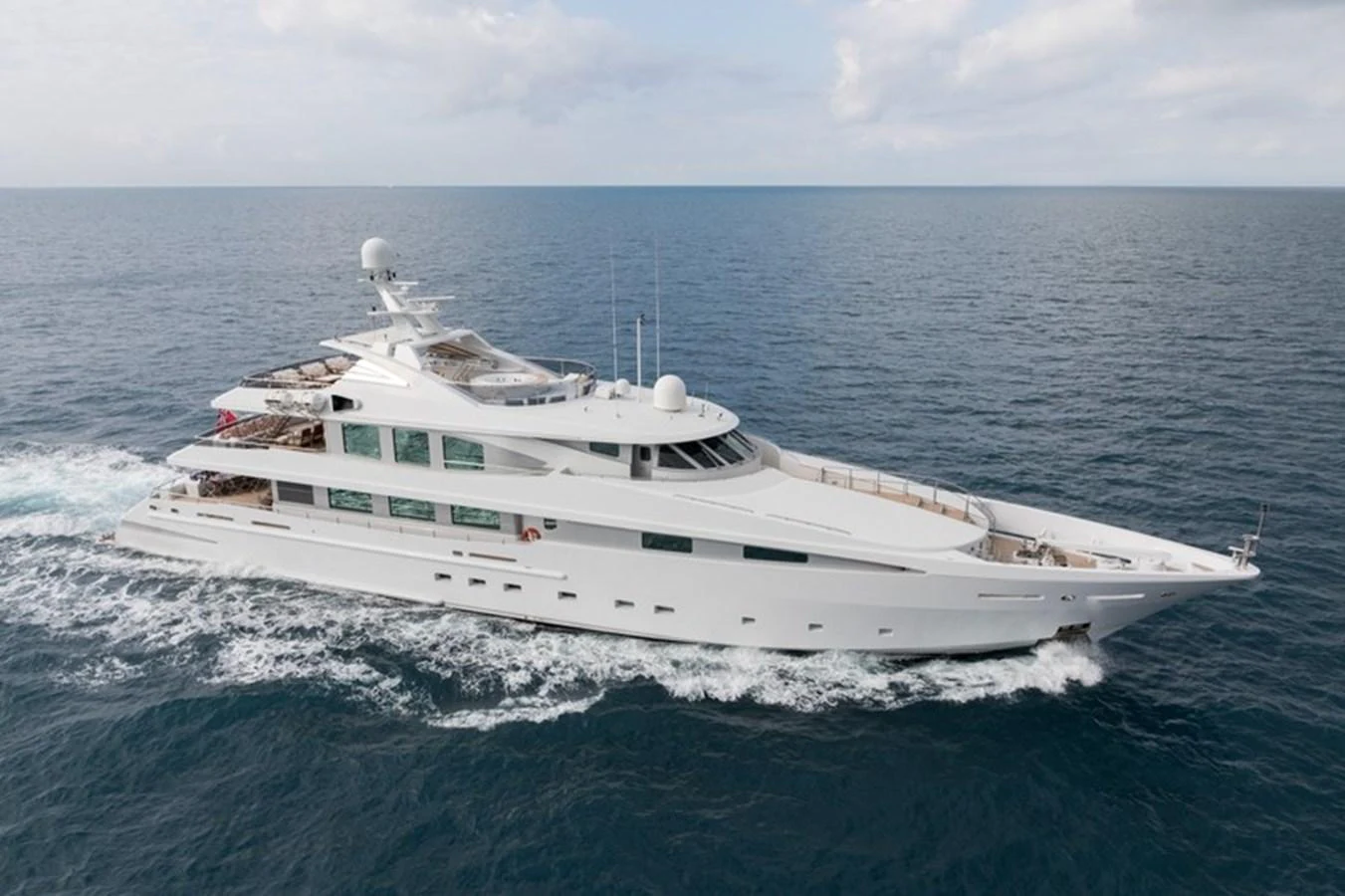A sleek and modern yacht cruising on open waters under a partly cloudy sky. aboard LA TANIA Yacht for Sale