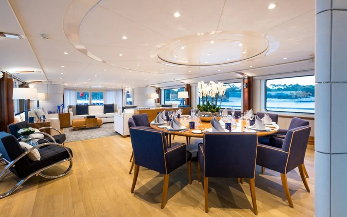 The yacht's elegant dining area features a beautifully set table with plush seating and panoramic windows offering stunning sea views. aboard LA TANIA Yacht for Sale