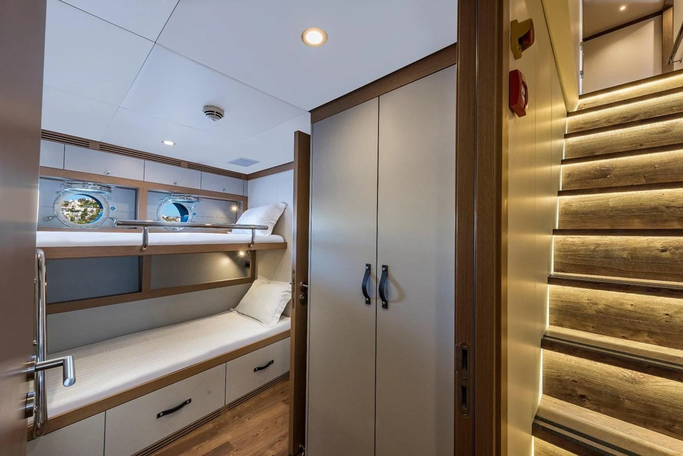 A cozy guest cabin with bunk beds and a wooden staircase leading to the upper deck. aboard CMB47-107 Yacht for Sale