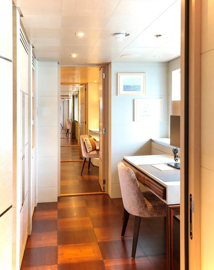 A bright and elegant hallway with a desk and chair, leading to other areas of the yacht. aboard HEESEN 47M Yacht for Sale