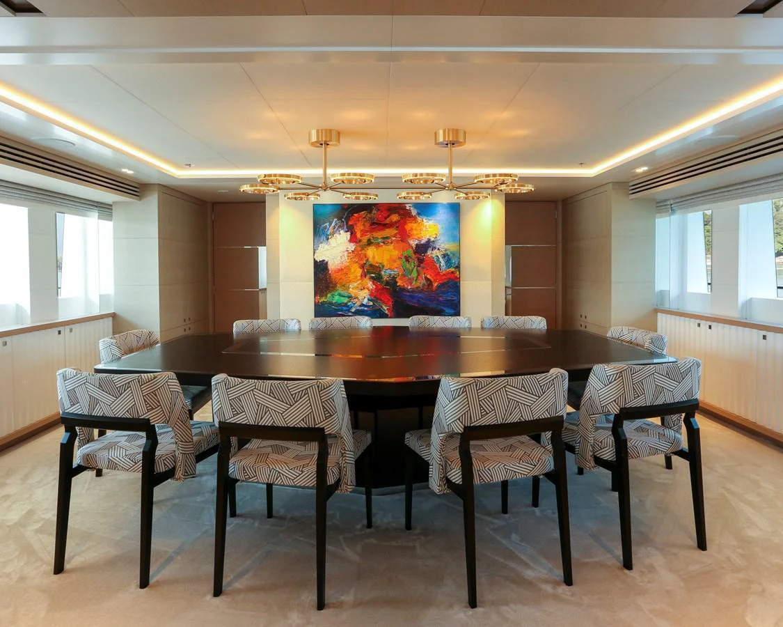 The yacht's dining area features a large table surrounded by stylish chairs and vibrant artwork. aboard HEESEN 47M Yacht for Sale