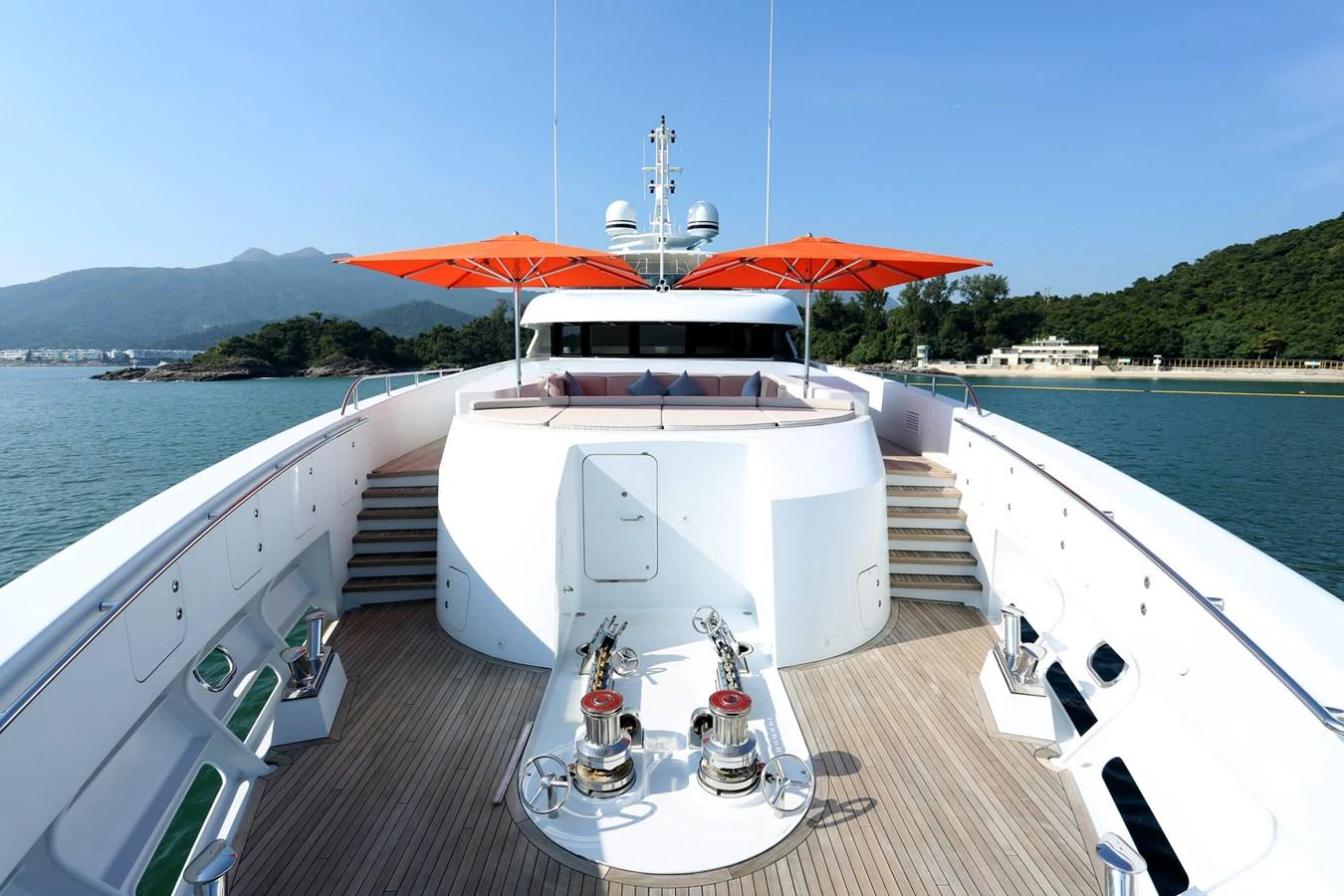 The foredeck features a spacious lounging area with vibrant orange umbrellas and polished deck fittings. aboard HEESEN 47M Yacht for Sale