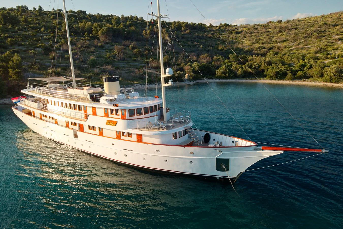 A classic yacht is anchored in a serene bay, showcasing its elegant design and spacious decks. aboard BELLEZZA Yacht for Sale