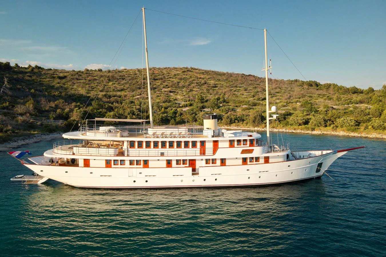 A classic luxury yacht is anchored in a serene bay, showcasing its elegant design and spacious decks. aboard BELLEZZA Yacht for Sale