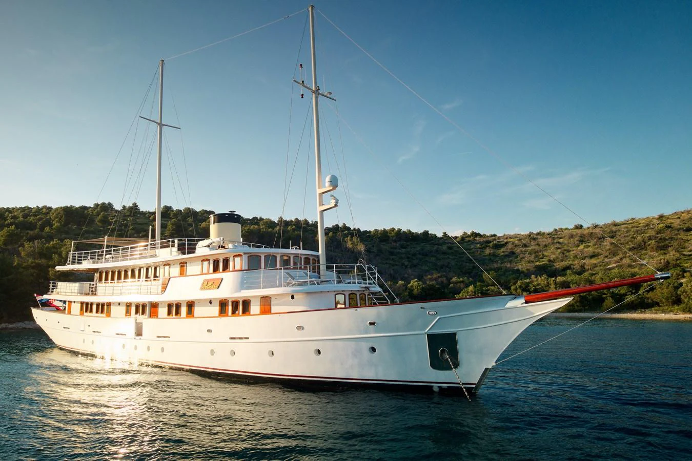A classic yacht with elegant lines cruising in serene waters under a clear sky. aboard BELLEZZA Yacht for Sale