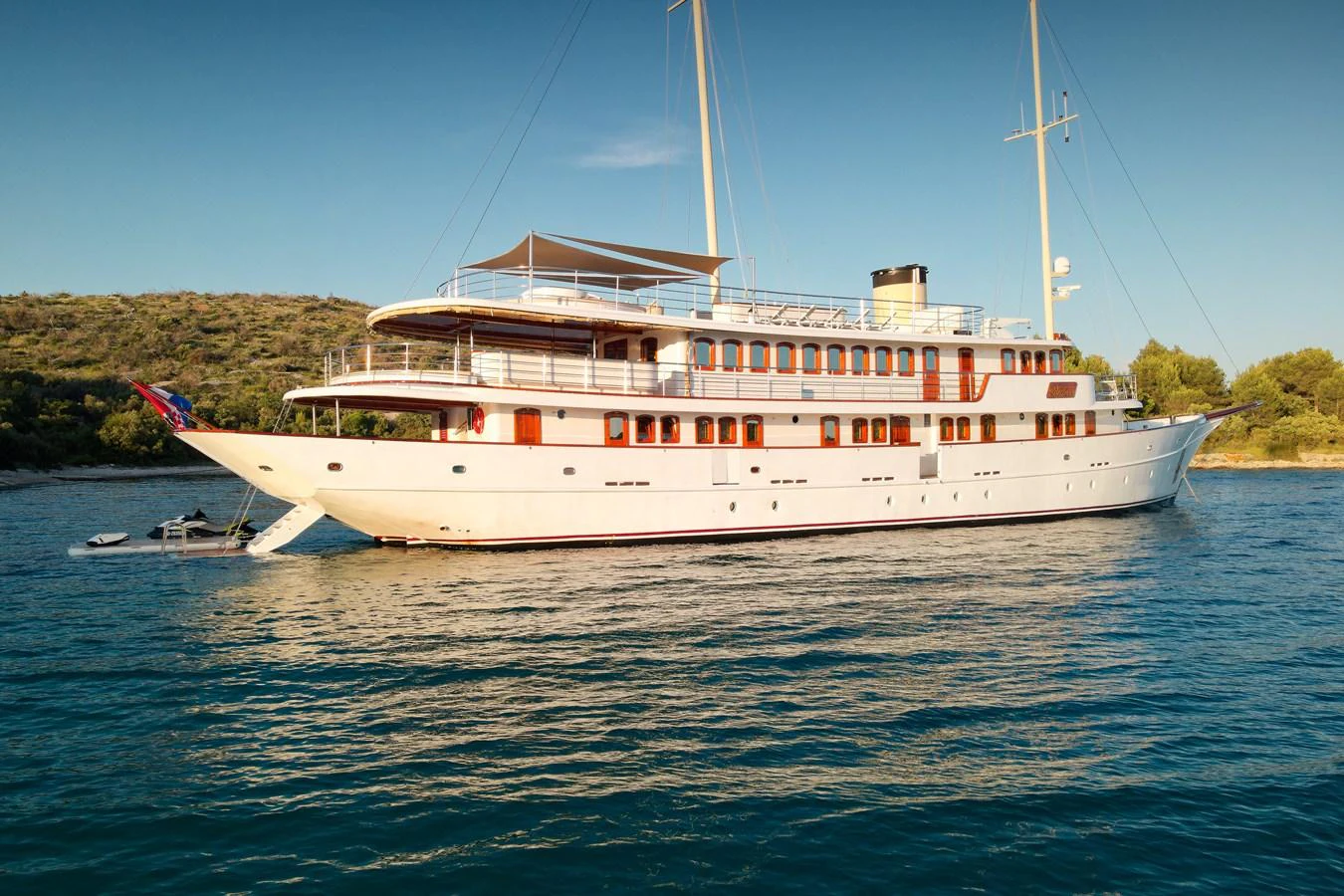 A classic yacht with elegant lines is anchored in serene waters, showcasing its timeless design. aboard BELLEZZA Yacht for Sale