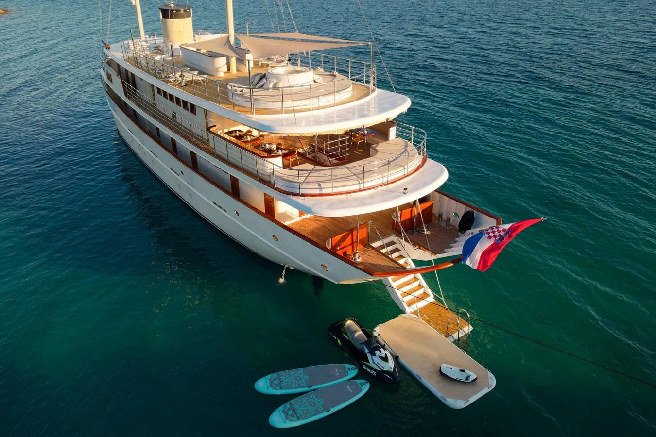 A luxurious yacht anchored in serene waters, featuring an inviting aft deck with water toys and a swim platform. aboard BELLEZZA Yacht for Sale