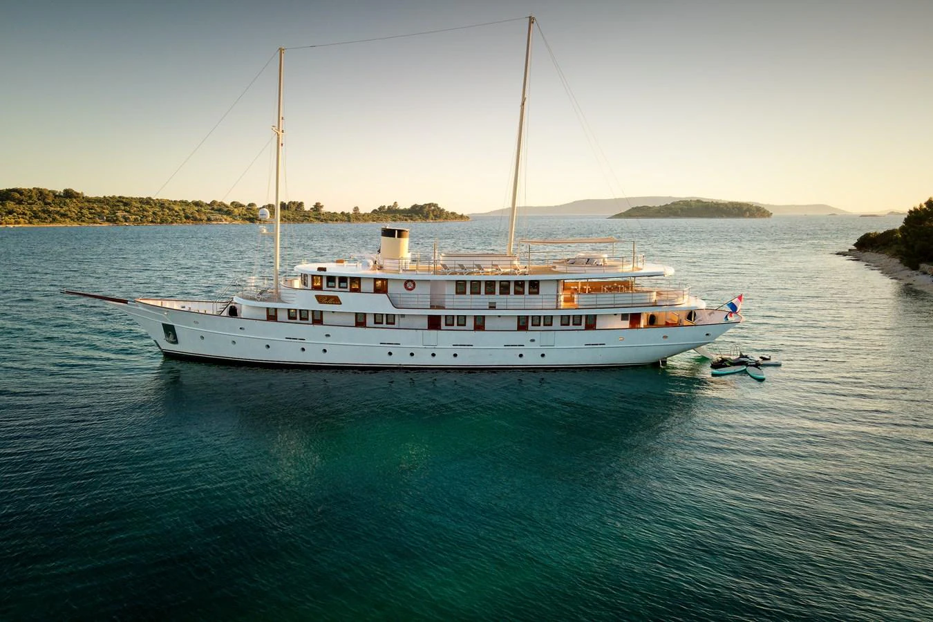 A stunning classic yacht is anchored in serene waters, showcasing its elegant design and timeless beauty. aboard BELLEZZA Yacht for Sale